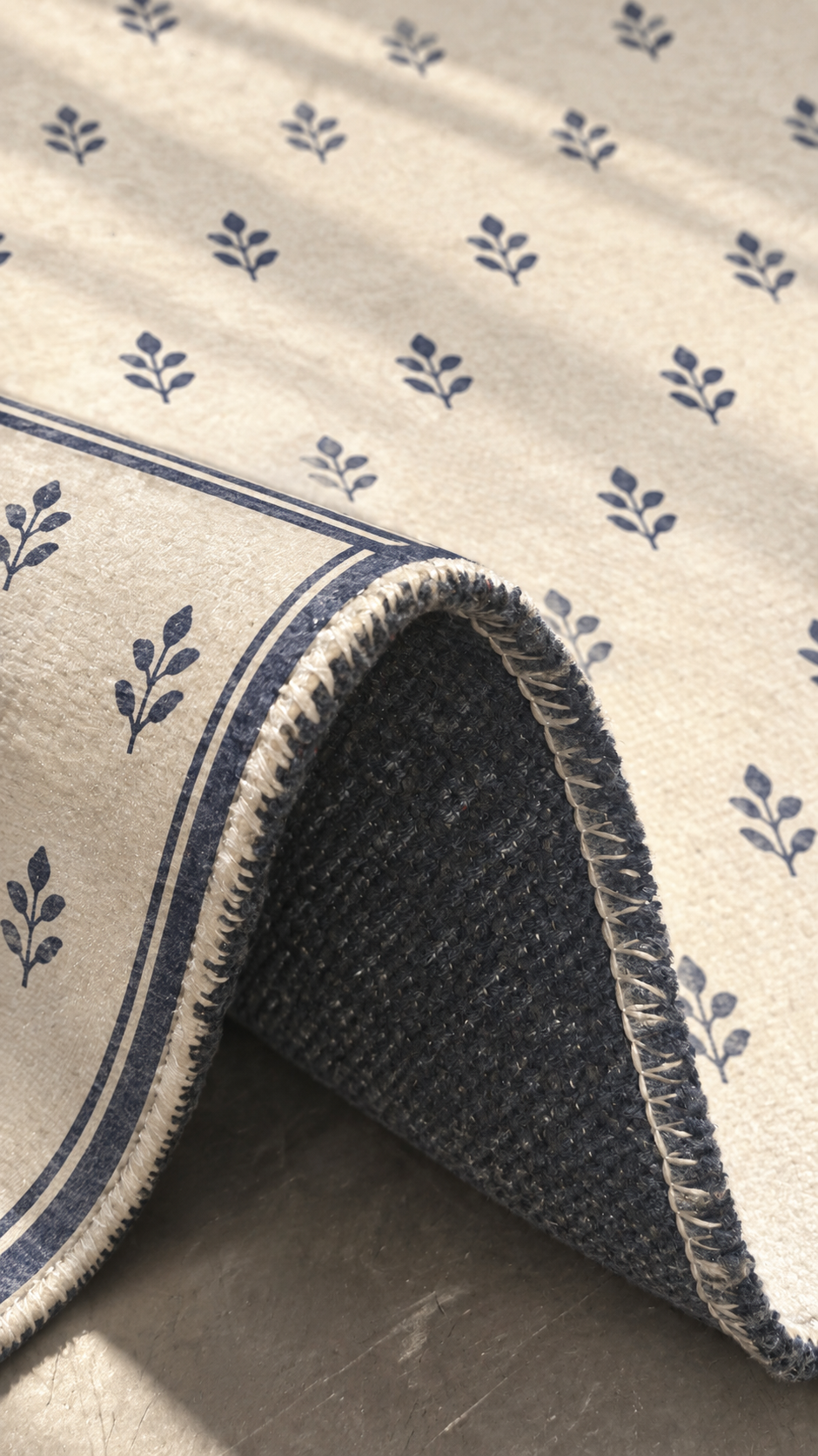 Apollo Little Orchard Area Rug — Navy / Cream — folded rug detail in soft afternoon light. Digital visualization.