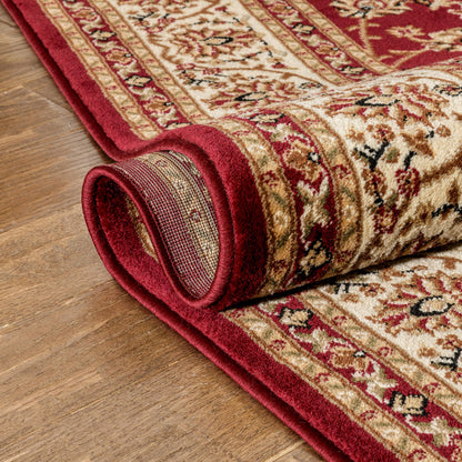 Rolling up a patterned red and beige rug on a wooden floor