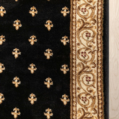 Close-up of a black rug with repeating gold medallion motifs and a wide ornate gold border, shown against a light wood floor.