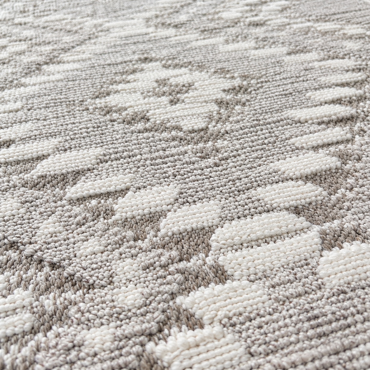 Close-up of a textured woven rug with a repeating geometric pattern in off-white and light gray.