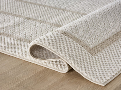 Lafayette Frame ivory and cream border area rug, rolled to show pile depth and the jute backing