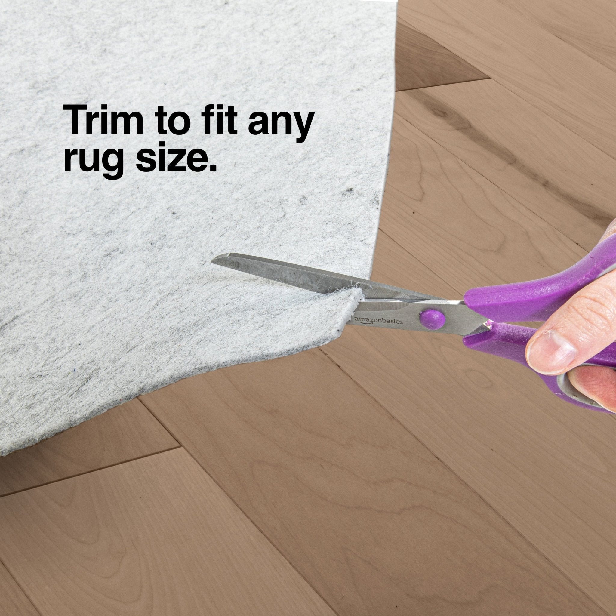 PAD-1 - Well Woven Premium Felt Non-Slip Rug Pad - Person using scissors to trim a felt rug pad on a wooden floor with text 'Trim to fit any rug size".