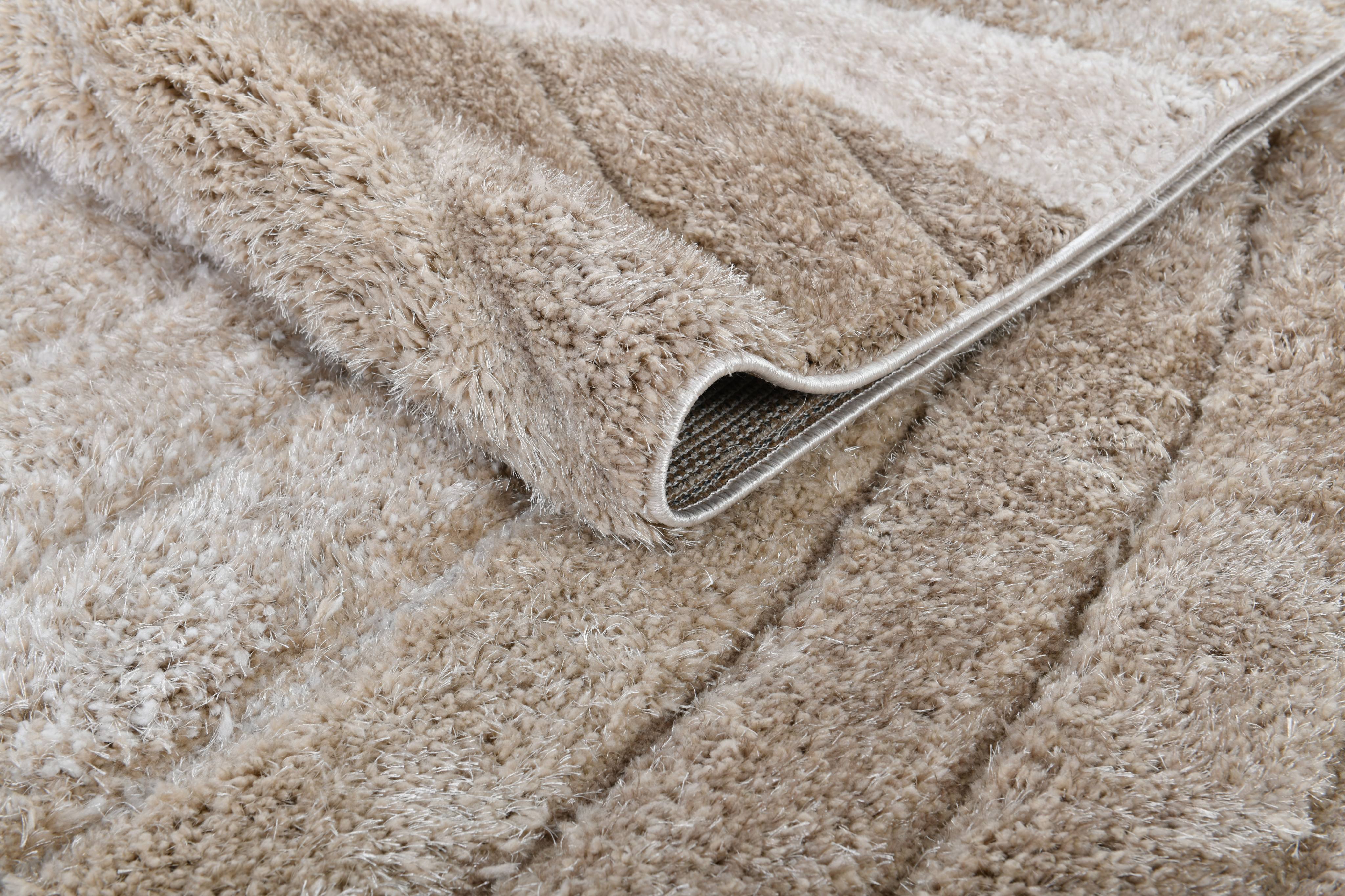 Corner detail of the Ucci beige shag rug showing thick plush pile and folded edge