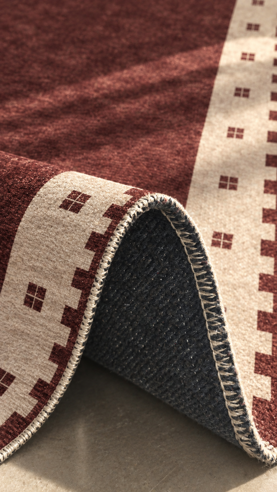 Apollo Evening Frame Area Rug — Burgundy / Cream — folded rug detail in soft afternoon light. Digital visualization.