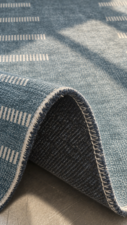 Apollo Interval Row Area Rug — Petrol Blue / Beige — folded rug detail in soft afternoon light. Digital visualization.