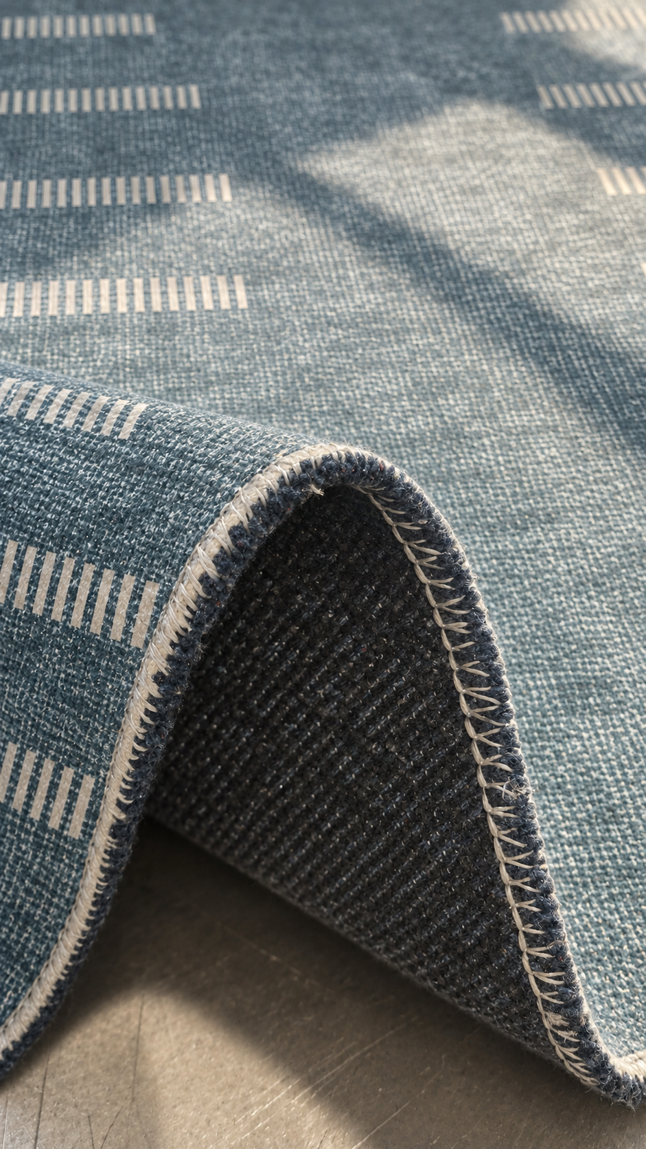 Apollo Interval Row Area Rug — Petrol Blue / Beige — folded rug detail in soft afternoon light. Digital visualization.