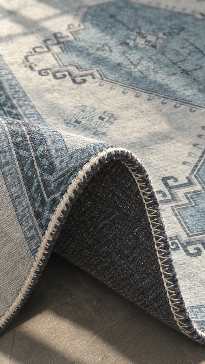 Apollo Wayfarer Court Area Rug — Petrol Blue / Beige — folded rug detail in soft afternoon light. Digital visualization.