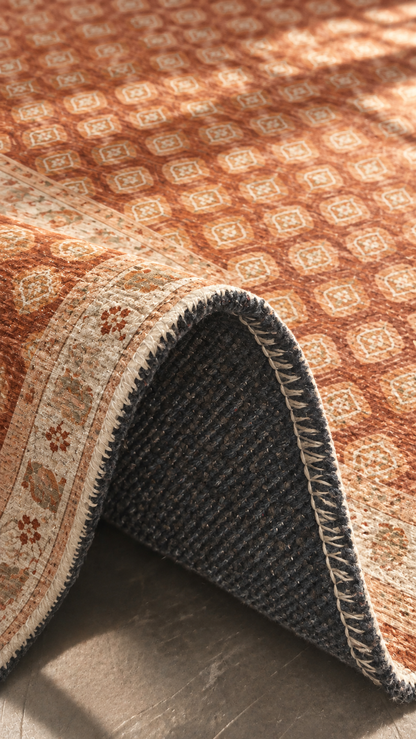 Apollo Filigree Lane Area Rug — Terracotta / Beige — folded rug detail in soft afternoon light. Digital visualization.