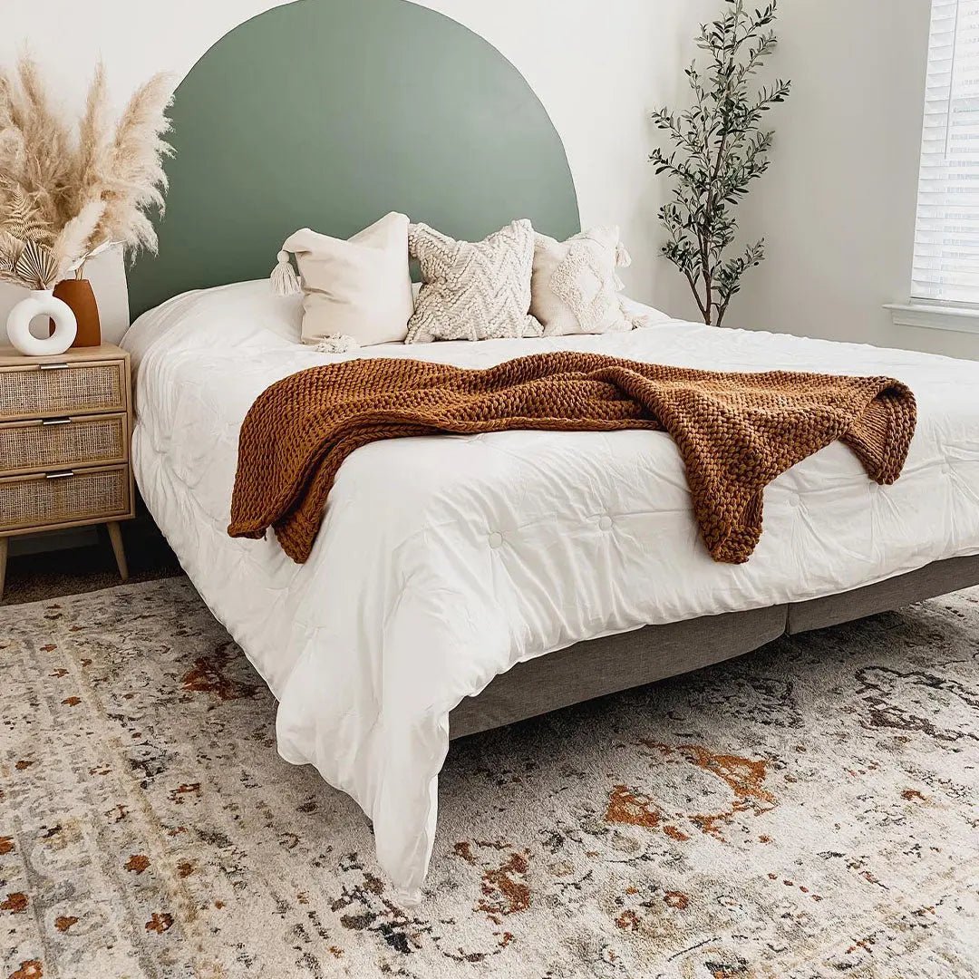 OM-122 – Bedroom with a white bed and a cream vintage distressed rug with rust and gray accents.